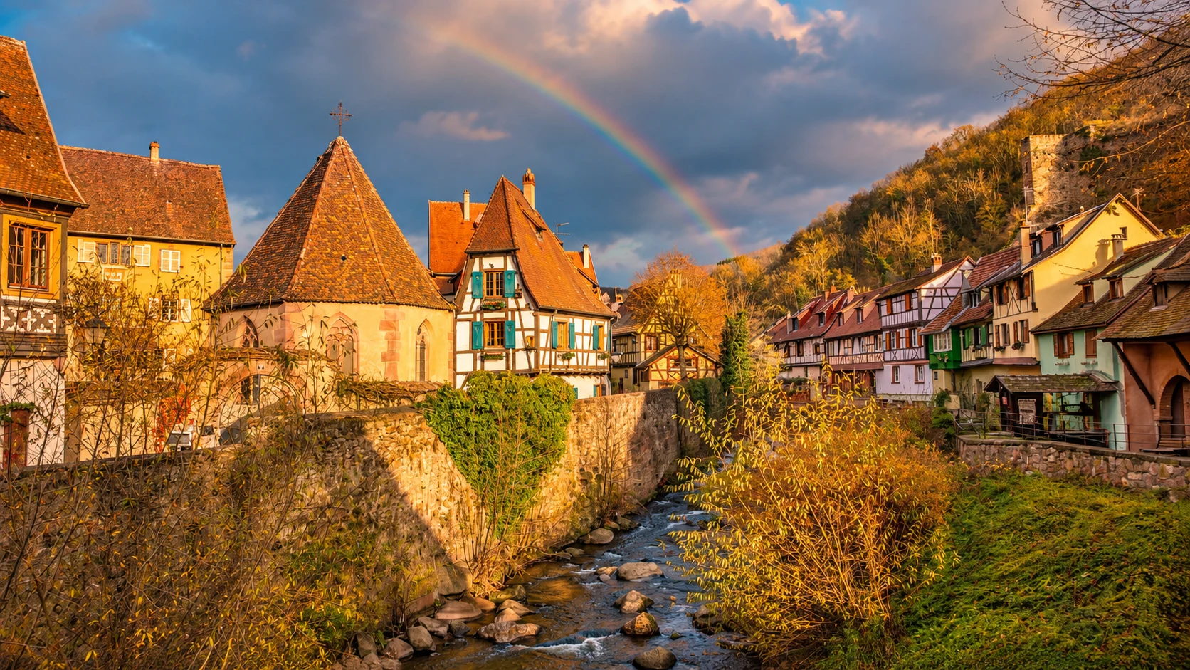 Traditional half-timbered houses with turquoise shutters, red-tiled roofs and colorful flowers in Kaysersberg, Alsace.
