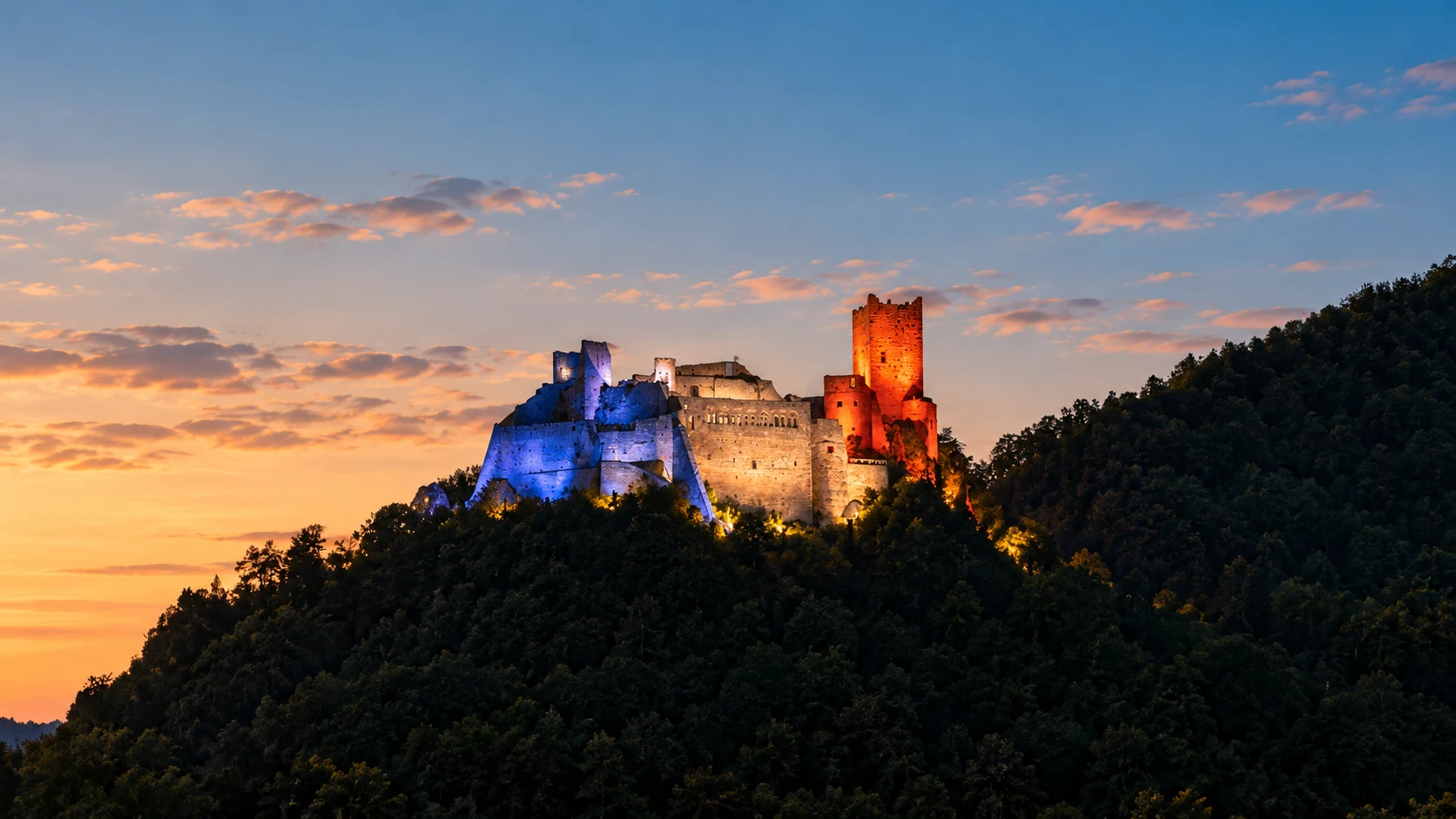 Saint-Ulrich Castle illuminated in blue, white and red above Ribeauvillé, Alsace, at dusk.