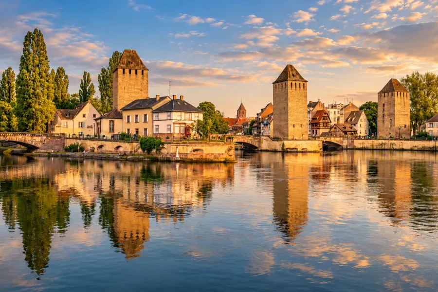 Panoramic view of Strasbourg’s Covered Bridges and three medieval towers reflected in the River Ill, Alsace.